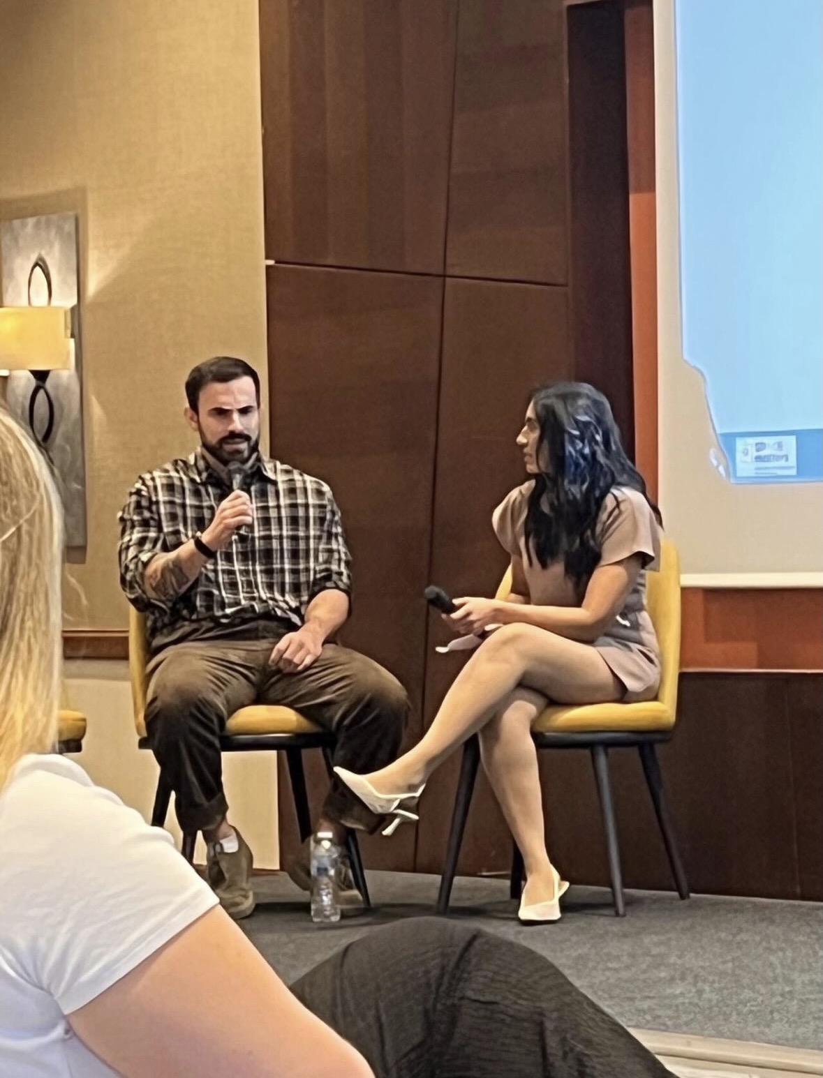 Ton Mazzone speaking into a microphone beside Dr Asha Patel on stage at SPACE Matters